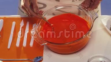 橙色物质从勺子滴到宽边的大玻璃锅里。